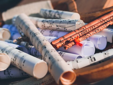 17c一起起草在线视频 编辑部内容主笔在暖光台灯下整理资料，桌面摊开笔记本与打印稿，专注核对信息的安静工作场景